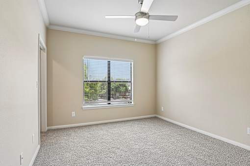 A room with a ceiling fan and a window with blinds.