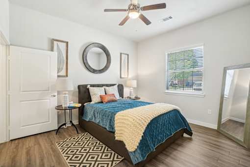 A bedroom with a bed, a ceiling fan, and a mirror on the wall.