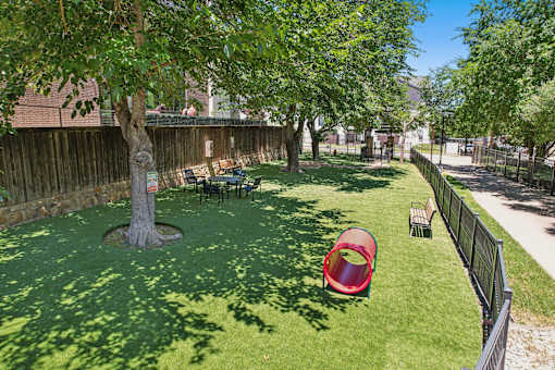 A backyard with a red slide and a green lawn.