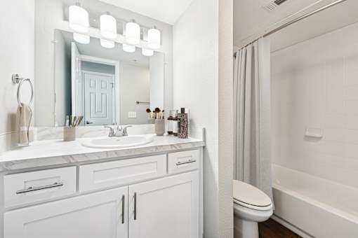 A white bathroom with a sink, mirror, and toilet.