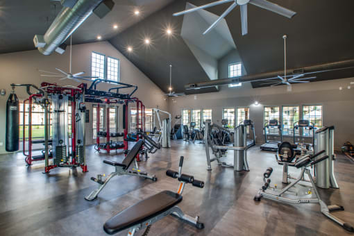 a spacious fitness center with exercise equipment and windows