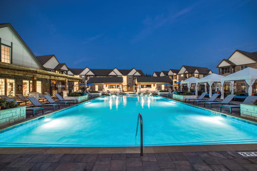 a resort style swimming pool with lounge chairs and umbrellas