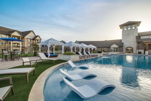 a resort style pool with lounge chairs and umbrellas