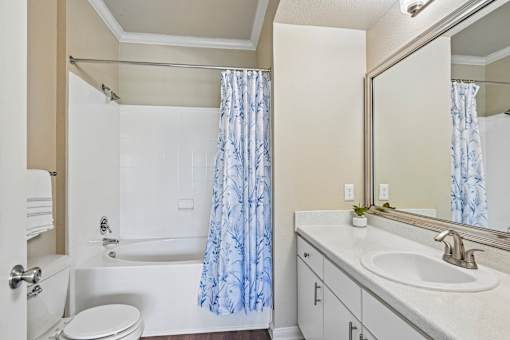 A white bathroom with a blue shower curtain.