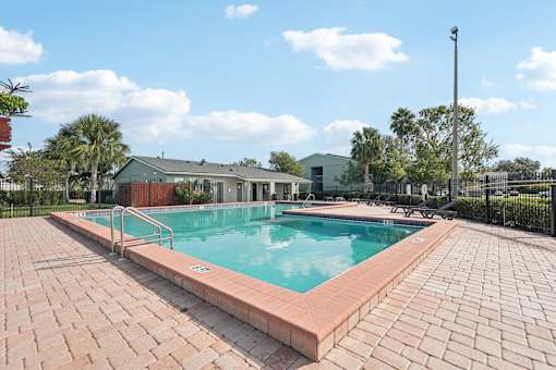 A pool surrounded by a brick patio.