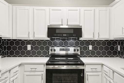 A kitchen with black and white tiles and white cabinets.