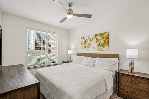 A bedroom with a bed, nightstand, and a painting on the wall.