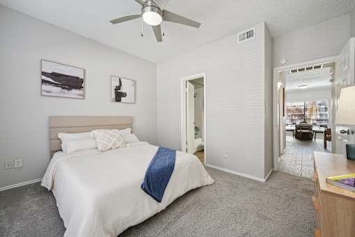 A bedroom with a bed, a ceiling fan, and a picture on the wall.