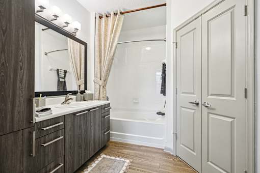 A bathroom with a wooden vanity and a white bathtub.