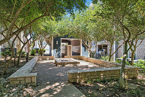 A courtyard surrounded by trees and a brick pathway.