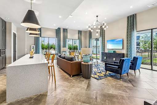 A modern living room with a large flat screen TV and a kitchen area.