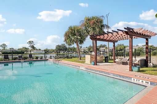 A pool with a pergola and palm trees in the background.