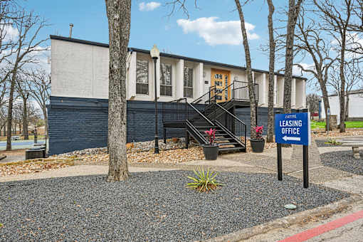 A blue sign with the words "LEASING OFFICE" stands in front of a building.
