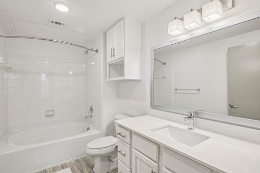 A white bathroom with a tub, toilet, and sink.