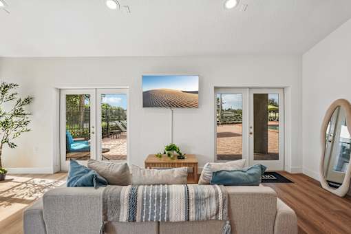 A living room with a grey couch and a large mirror on the wall.