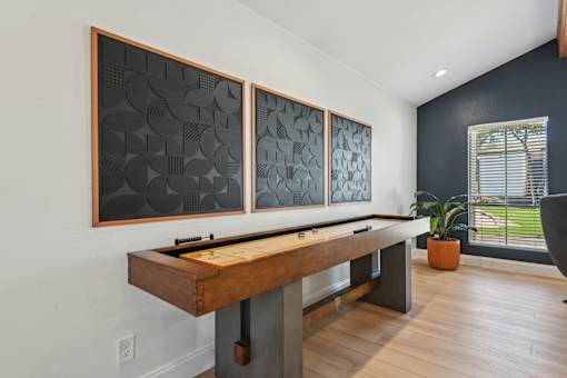 A room with a shuffleboard table and three artworks on the wall.