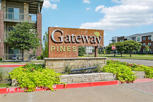 A sign that says "Gateway Pines" in front of a building.