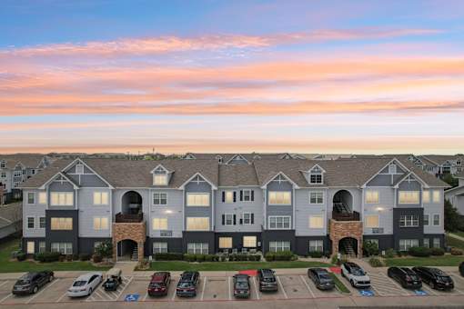A large apartment complex with a parking lot in front.