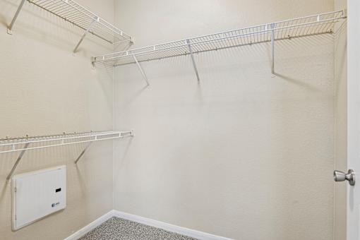 A walk-in closet with a white door and shelves.