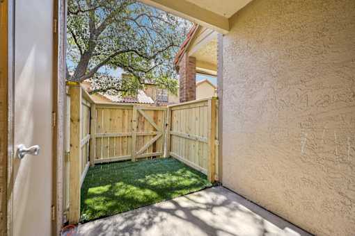 A wooden gate opens to a backyard with a green lawn.