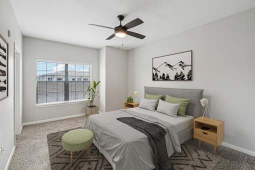 A bedroom with a bed, a chair, and a ceiling fan.