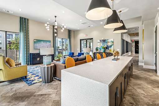 A modern living room with a white counter and orange chairs.
