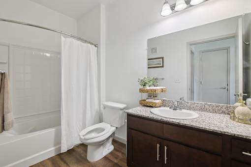 A white toilet sits in a bathroom with a white shower curtain.
