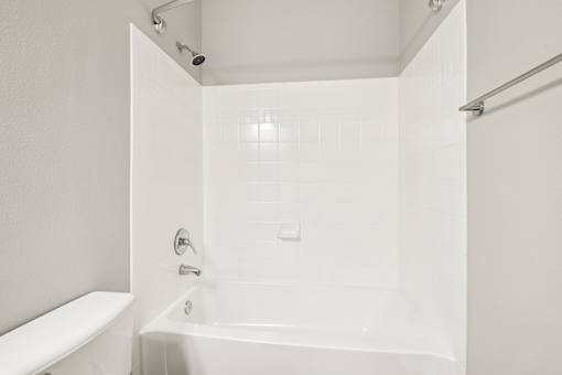 A white bathroom with a tub, toilet and shower.