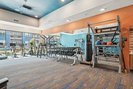 A gym with a variety of equipment including weights and a leg press machine.