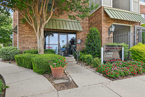 A leasing center sign is in front of a building with a brick facade and a green awning.
