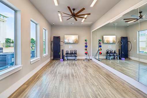 A gym with a mirror, weights, and exercise equipment.