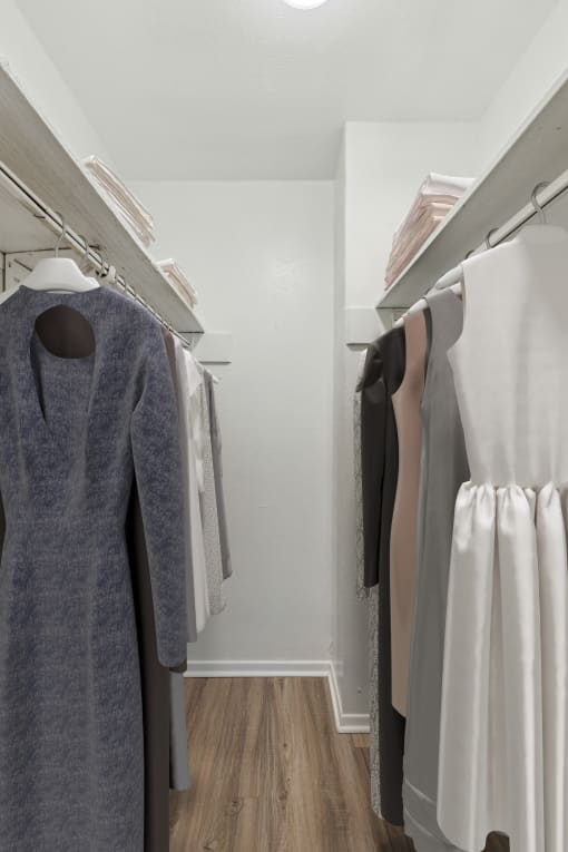 a walk in closet with a grey dress on a hanger and white dresses on a rack