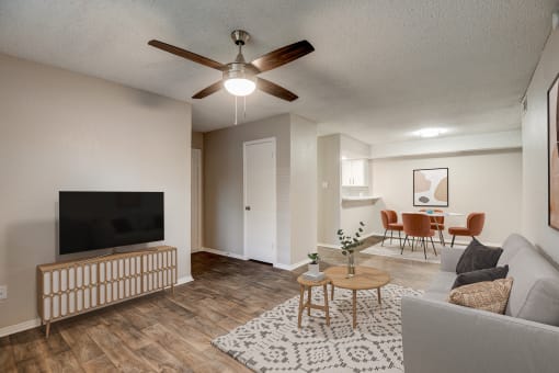 a living room with a ceiling fan and a dining room in the background