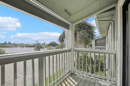 A balcony with a view of a body of water and trees.
