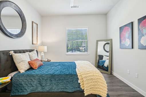 A bedroom with a bed covered in a blue and yellow blanket.