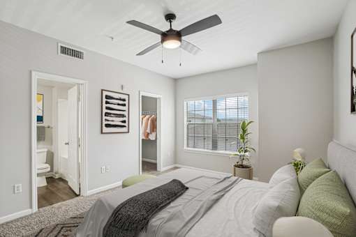A bedroom with a bed, a ceiling fan, and a window with blinds.