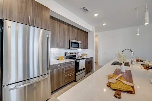 A modern kitchen with a stainless steel refrigerator and wooden cabinets.