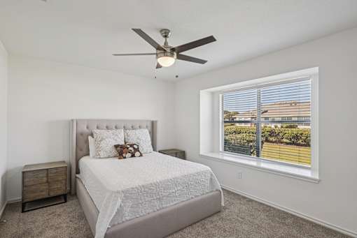 A bedroom with a bed, nightstand, and window.