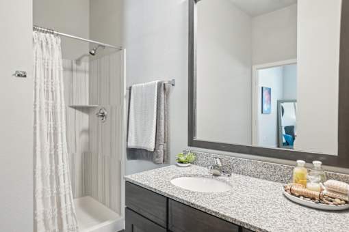 A bathroom with a white shower curtain and a white towel hanging on the shower rod.