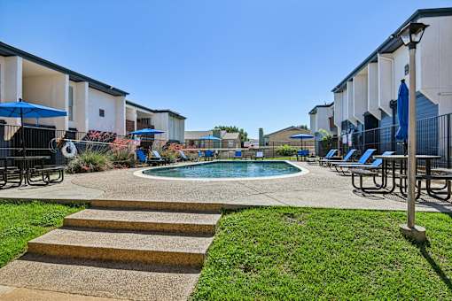 A pool surrounded by a concrete patio and steps.