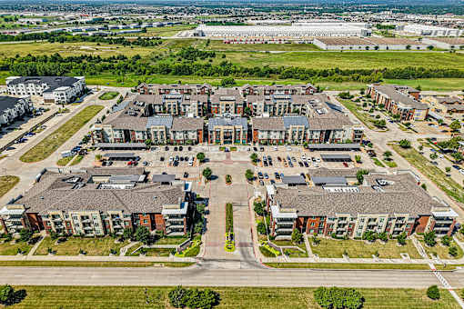A large apartment complex with a parking lot in front.