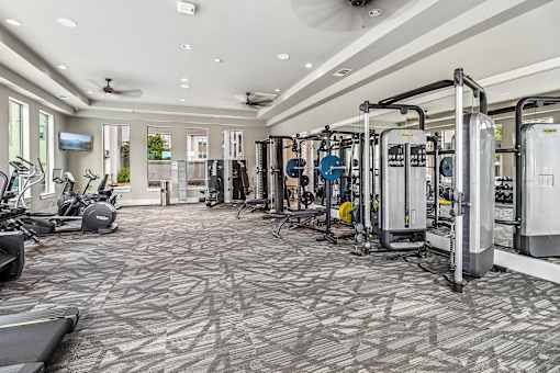 A spacious gym with a variety of equipment and a patterned carpet.