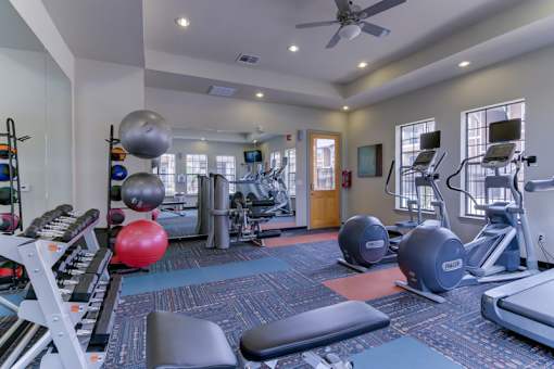 A gym with a variety of equipment including weights and cardio machines.