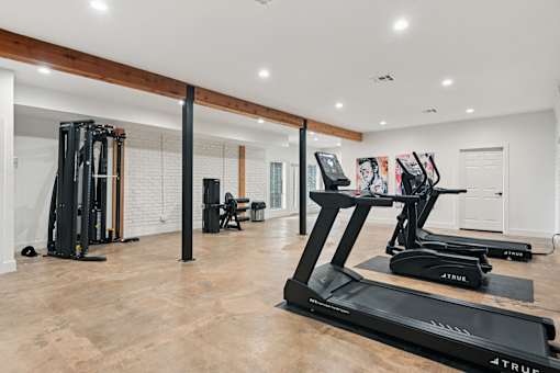 A gym with a treadmill, a stationary bike, and a rowing machine.