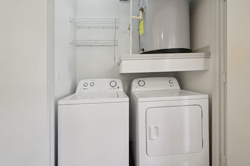 Two white washing machines in a small laundry room.
