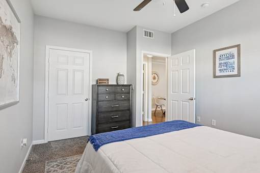 A bedroom with a bed, dresser, and ceiling fan.