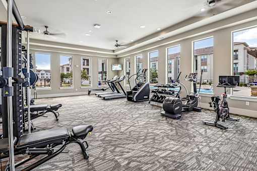 A spacious gym with a variety of equipment including treadmills, stationary bikes, and weight machines.