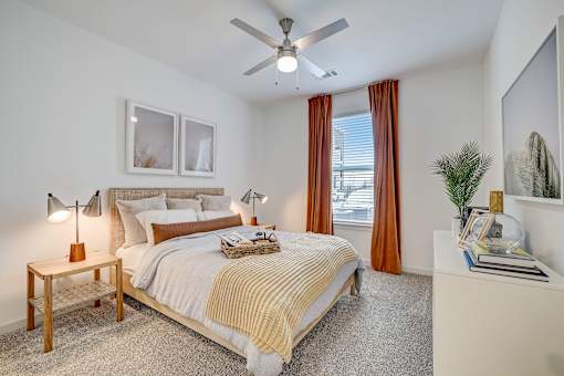 A bedroom with a bed, nightstand, and a ceiling fan.