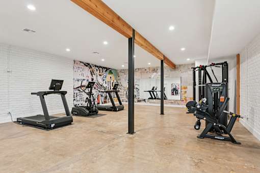 A gym with a variety of equipment including treadmills, rowing machines, and weight machines.