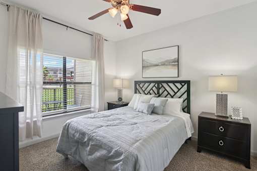 A bedroom with a bed, nightstands, and a ceiling fan.